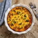 Freshly baked broccoli cheddar crustless quiche in a white pie dish